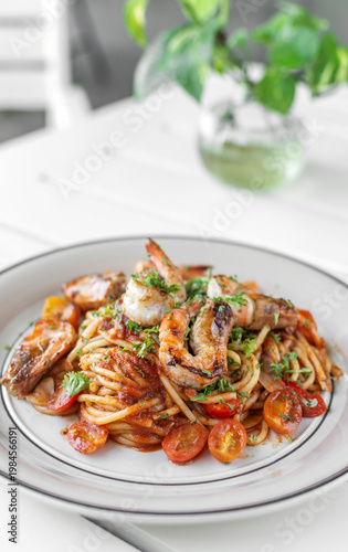 shrimp and tomato diavolo spicy spaghetti on white table at outdoor restaurant in italy