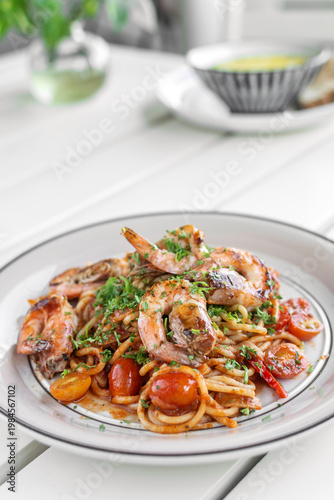 shrimp and tomato diavolo spicy spaghetti on white table at outdoor restaurant in italy