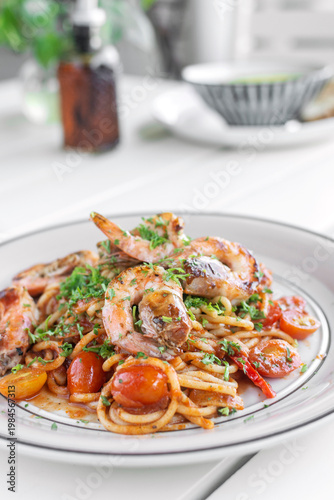 shrimp and tomato diavolo spicy spaghetti on white table at outdoor restaurant in italy