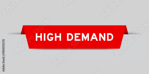 Red color inserted label with word high demand on gray background