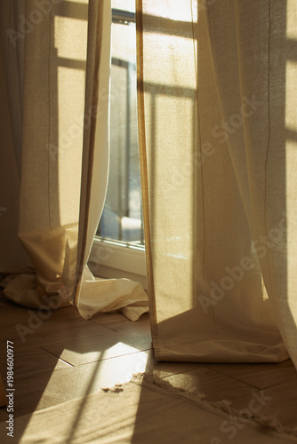 Fotografie Sunlight streaming through beige linen curtains in a cozy room at golden hour