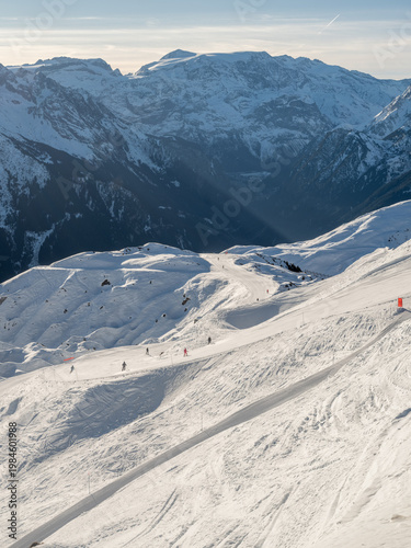 ski run in the French Alps of le plagne focusing on a tight right turn, with white crisp slopes set against a background of snow capped mountains. 
