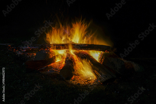 Beautiful image of camp and fireplace fire burning in the dark at night.
