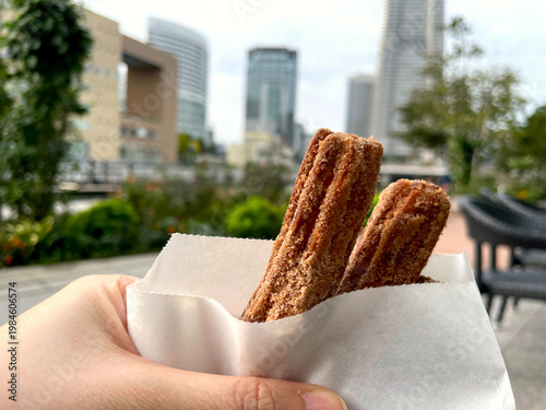 Wallpaper Mural チュロス ─ 手持ち紙袋のシナモンシュガーチュロス2本・屋外 Torontodigital.ca