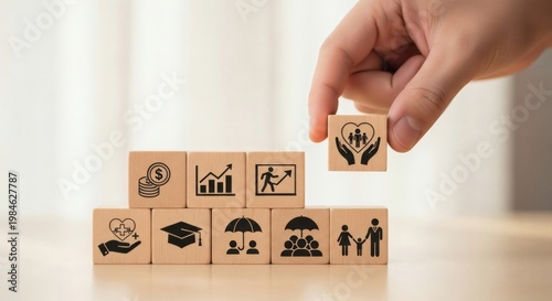 Employee Benefits and Workplace Support System Concept. Hand placing care icon cube above  blocks with finance growth family education and health symbols, representing inclusive benefits strategy.
