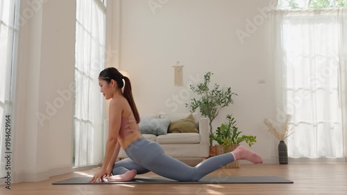 Asian woman practicing King Pigeon yoga pose at home