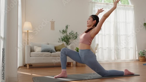 Beautiful Asian woman practicing Crescent Lunge yoga pose at home