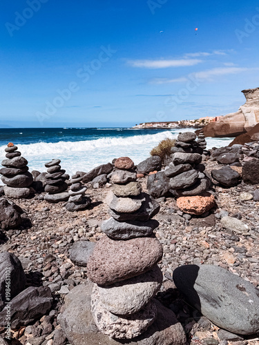 Stone cairns on volcanic beach with ocean waves, Playa del Duque Norte, Tenerife