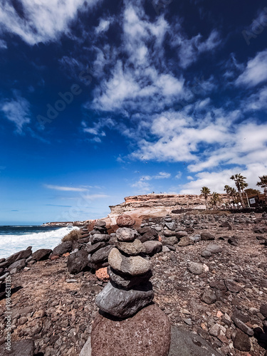 Stone cairns on volcanic beach with ocean waves, Playa del Duque Norte, Tenerife