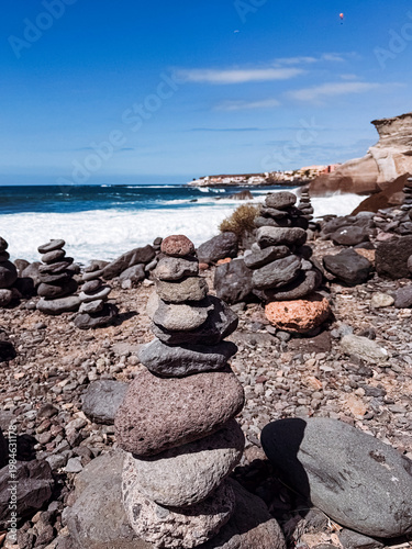 Stone cairns on volcanic beach with ocean waves, Playa del Duque Norte, Tenerife