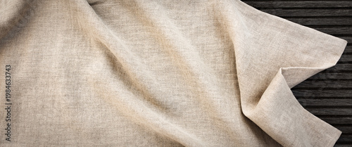 Light beige linen fabric with folds and natural texture. Natural-colored background for product presentations and weddings.