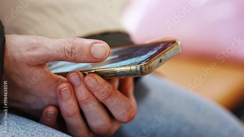 Person checks phone for messages while seated in a cafe