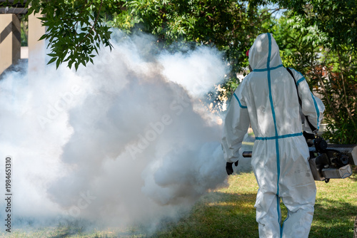 Bild auf Leinwand Rear view of an exterminator in a white chemical protection suit using a machine outdoors