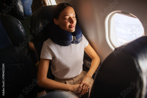 Bild auf Leinwand Lady sitting in seat on plane with eyes closed, using neck pillow for comfort du