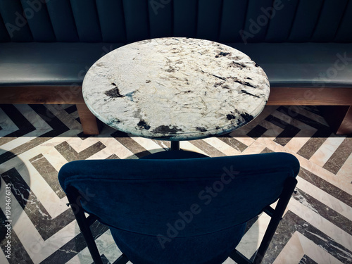 Elegant Round Marble Table with Blue Chair in Stylish Modern Cafe Interior with Geometric Floor Pattern