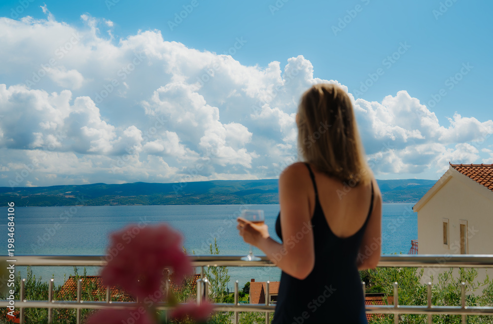 Obraz premium Woman admiring sea view from resort balcony.