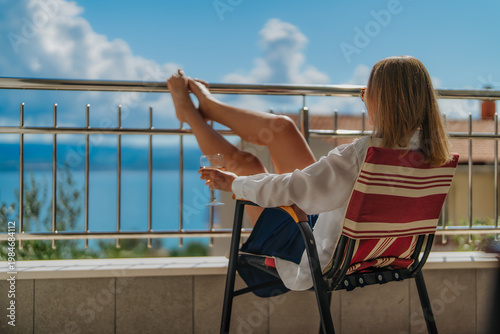 Woman relaxes on terrace overlooking the sea.