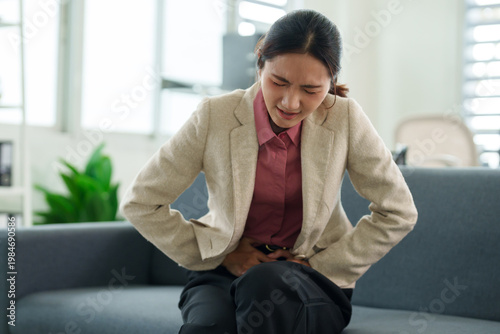 Foto Pain and discomfort: An individual in professional attire experiences abdominal pain, her expression and posture indicative of a struggle with an internal ailment