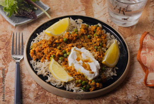 Beef kemma curry garnished with yogurt and lemon wedges.