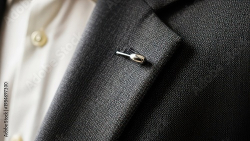 Close-up of a suit jacket lapel with a silver pin, showing shirt collar underneath