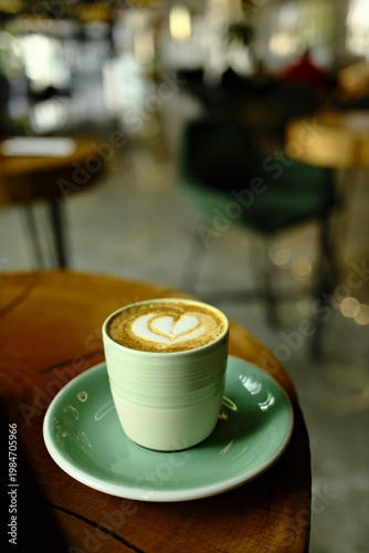 Latte coffee on wooden table in cozy cafe with blurred background