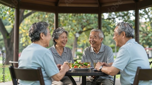Joyful elderly friends sharing a meal outdoors in a park gazebo