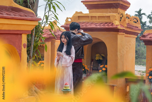 Fotografie An Asian older brother and his younger sister practicing ancestral worship at a traditional vibrant shrine, symbolizing deep-rooted filial piety