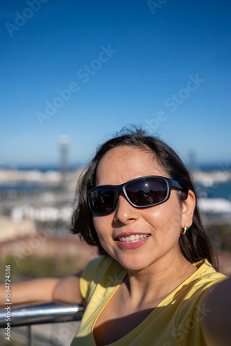 Latin woman wearing sunglasses, smiling for a selfie while traveling and enjoying tourism