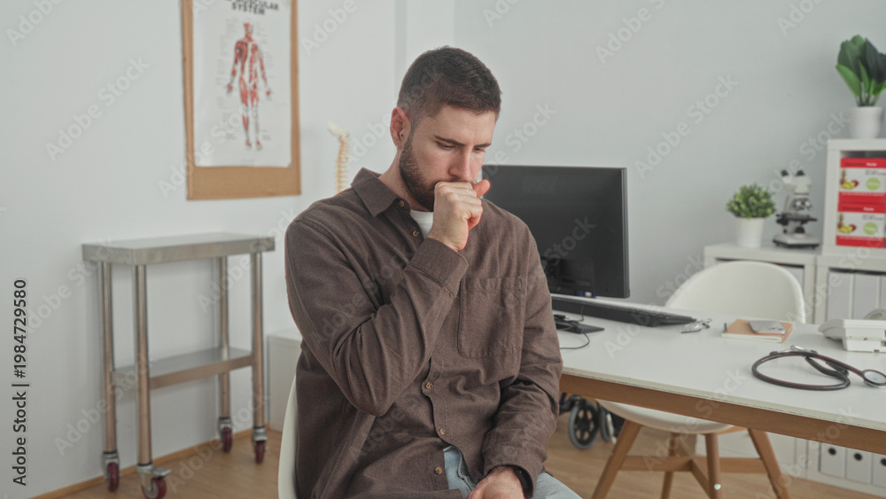 Fototapeta premium Man clutching chest seated at a desk with stethoscope in a medical building, coughing and wincing; anxiety illness.