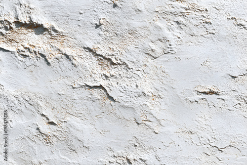 Close-up of a textured white wall with peeling paint and rough surface details.