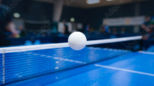 Ping pong ball bouncing above table tennis table during sports match. Dynamic indoor competition scene with speed, motion and table tennis equipment.