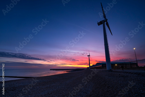 Sunset along coast with pair of land-based wind turbines
