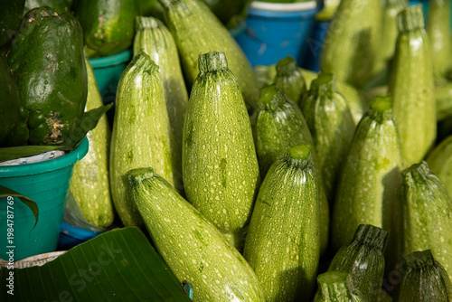 Fresh green zucchini displayed at a vibrant outdoor market stall in San Cristobal de las Casas, Chiapas, Mexico.