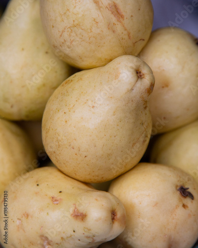 Fresh pears displayed in buckets at a vibrant Mexican market stall in Chiapas, Mexico.