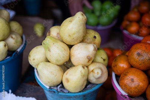 Fresh pears displayed in buckets at a vibrant Mexican market stall in Chiapas, Mexico.