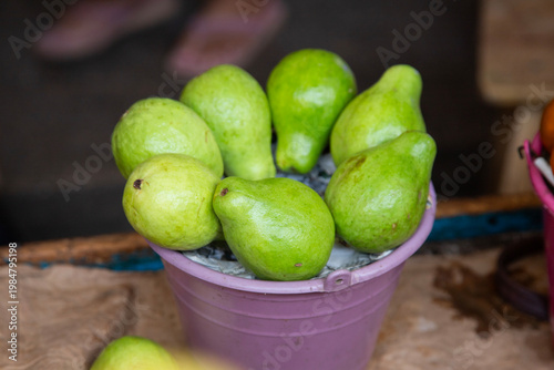 Fresh pears displayed in buckets at a vibrant Mexican market stall in Chiapas, Mexico.