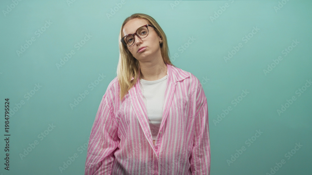 Obraz premium Woman wearing glasses tilts head back with closed eyes in a studio wearing pink striped blouse and white tee; fatigue contemplation.