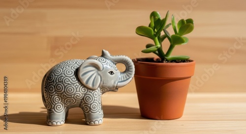 Small Ceramic Elephant Figurine with Intricate Swirl Pattern Next to Potted Succulent Plant on Wooden Surface