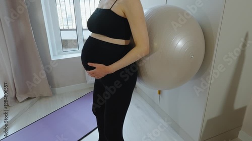 Massage and strengthening back and pelvic floor muscles. Fitness for pregnant women. Close-up of pregnant woman squatting with fitball, leaning against wall. Exercises for pregnant in late pregnancy.