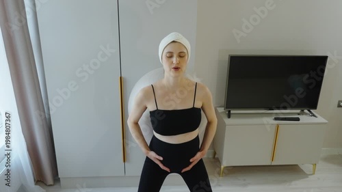 Fitness for pregnant women at home. Portrait of pregnant woman squatting with fitball, leaning against a wall. Exercises in late pregnancy. Massage and strengthening the back and pelvic floor muscles.