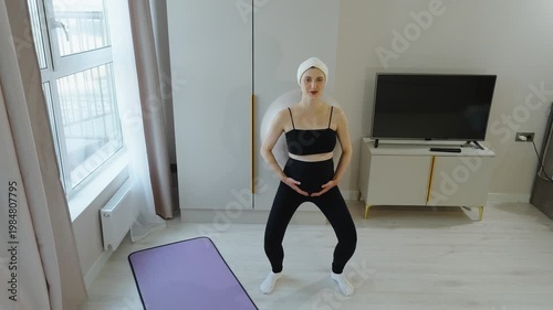 Fitness for pregnant women. Pregnant woman doing squats with fitball, leaning against wall. Gymnastics for pregnant women in late pregnancy. Prenatal training, fitness, preparing for childbirth.