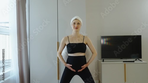 Gymnastics in late pregnancy. Prenatal training, fitness for pregnant women, preparing for childbirth, healthy lifestyle during pregnancy. Portrait of pregnant woman doing squats with fitball.
