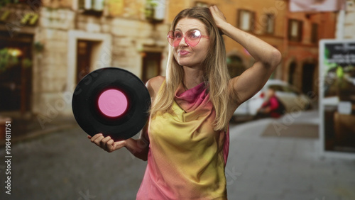 Foto Woman holding vinyl record with hand on head and pink sunglasses on a cobbled street; nostalgia retro