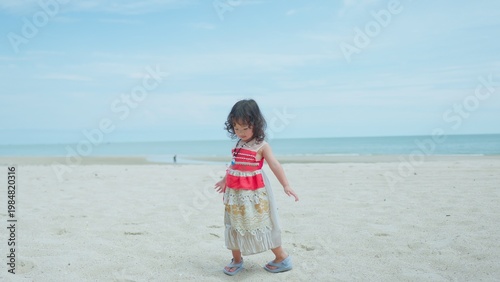 фотографія A young toddler in a tribal costume turns around on a sandy beach, enjoying imaginative play and freedom during a beautiful summer family vacation by the sea