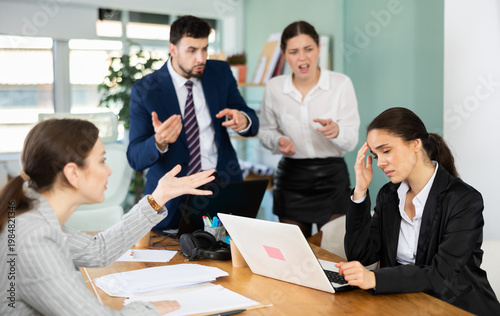 Obraz na plátne Group of women and man scold young woman while she sits looking sad in office