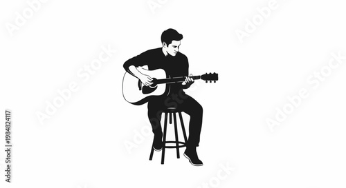 A young man plays an acoustic guitar while sitting on a stool