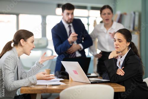 Bild auf Leinwand Woman employee in the office feels resentment and guilt against the background of her colleagues scolding her