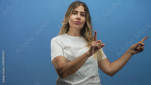 Fotografia Woman middle aged wearing white t shirt pointing index finger with both hands toward the right on a blue studio backdrop; playful confidence