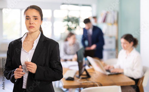 фотографія Upset female employee feeling hurt while colleagues work in blurred background o