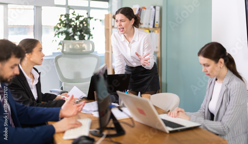 Εκτύπωση καμβά Young woman stands at office desk and scolds group of upset man and women in off